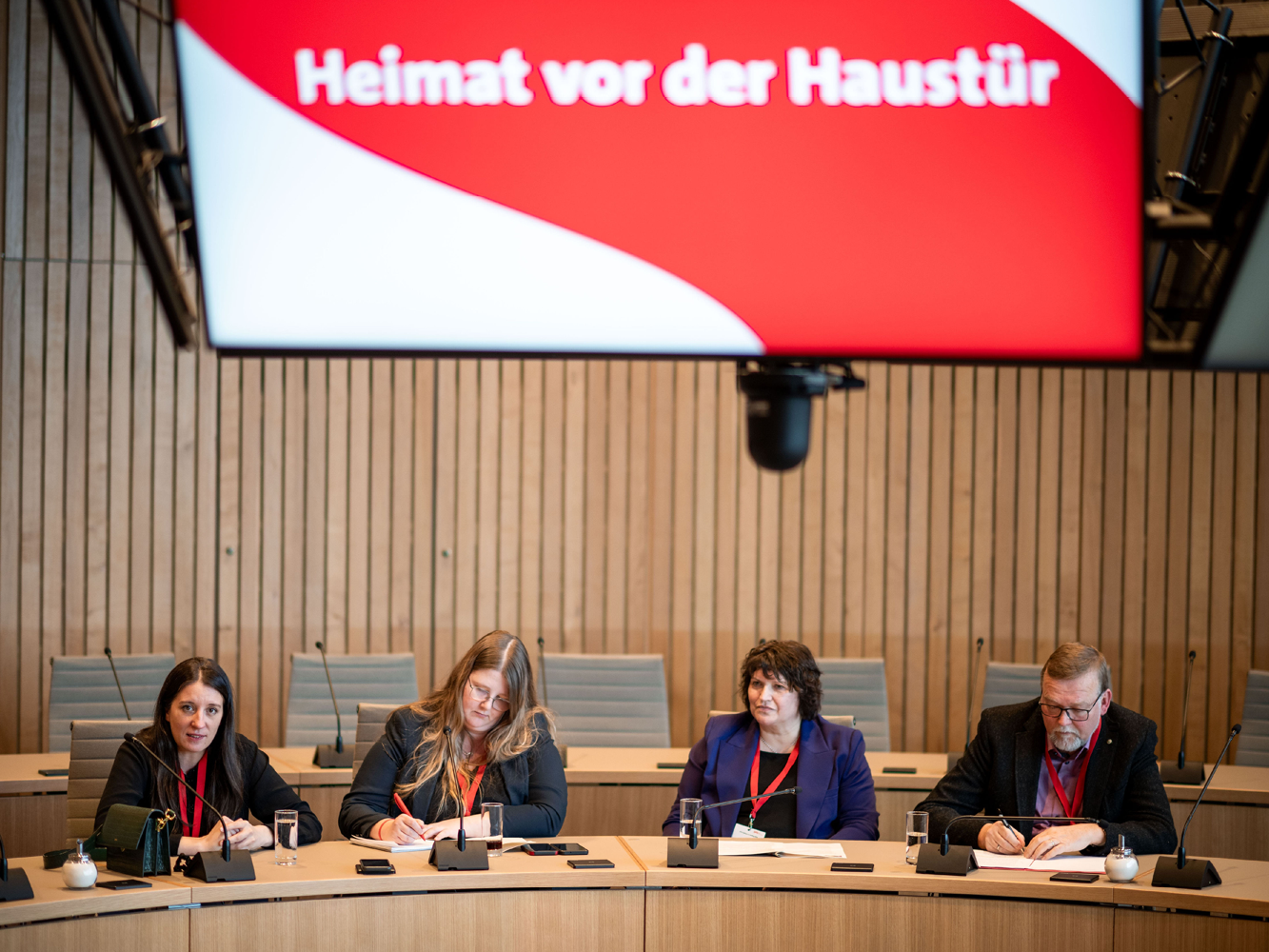 © SPD-Fraktion im Landtag NRW Ralf Zimmer-Hegmann sitzt mit drei Frauen an einem Tisch des Sitzungssaals und notiert sich etwas auf einem Zettel. Eine Frau schaut in die Kamera, eine Frau notiert sich ebenfalls etwas und eine Frau schaut nach links aus dem Bild raus.